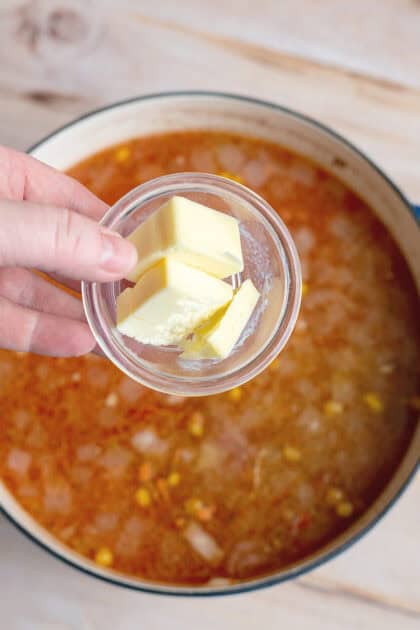 Adding butter to pot of chicken stew.
