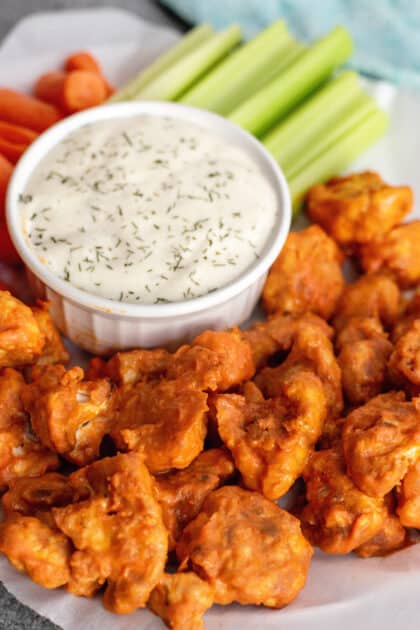 Plate of cauliflower buffalo bites with ranch and vegetable sticks.