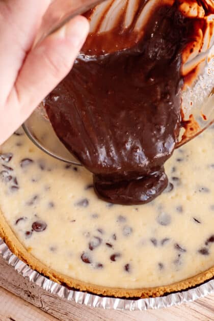 Pour ganache over chocolate chip cheesecake.