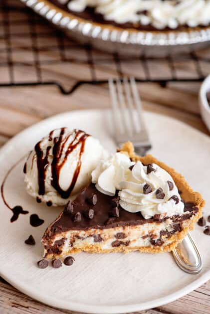 Slice of chocolate chip cheesecake with ice cream and chocolate syrup.