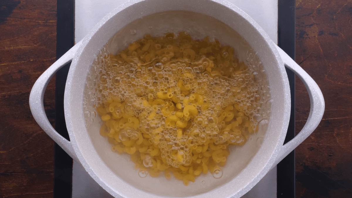 Cooking elbow pasta over the stove.