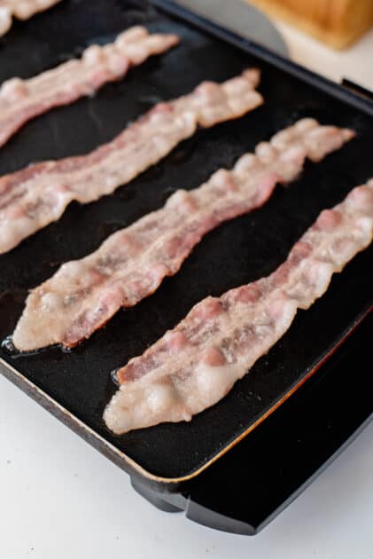 Fry bacon strips.