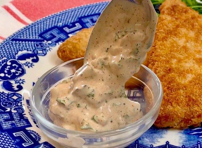 Spoonful of homemade tartar sauce with fish fillets.