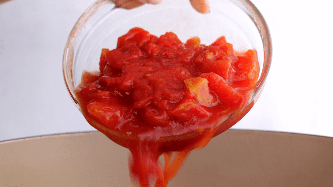 Pour half the canned tomatoes in pan.