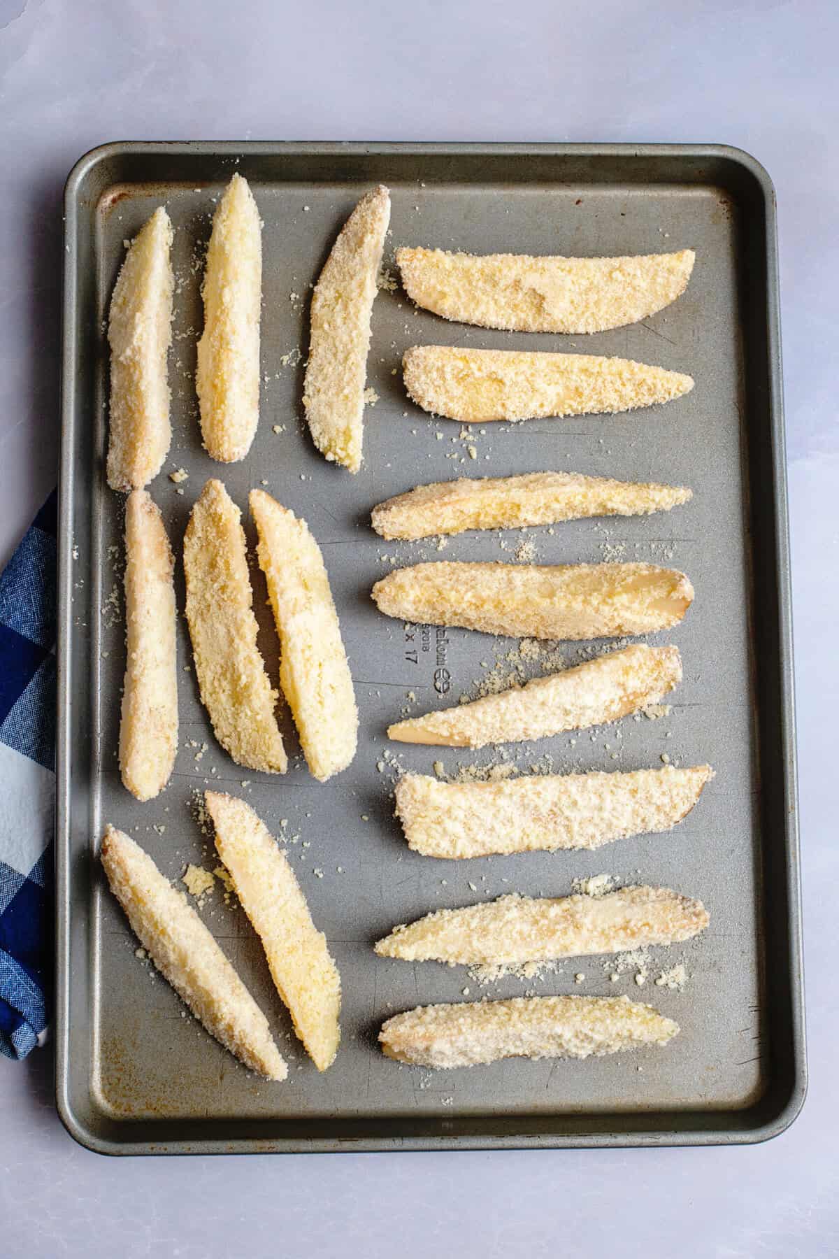 Parmesan coated oven fries on a baking sheet before getting baked.