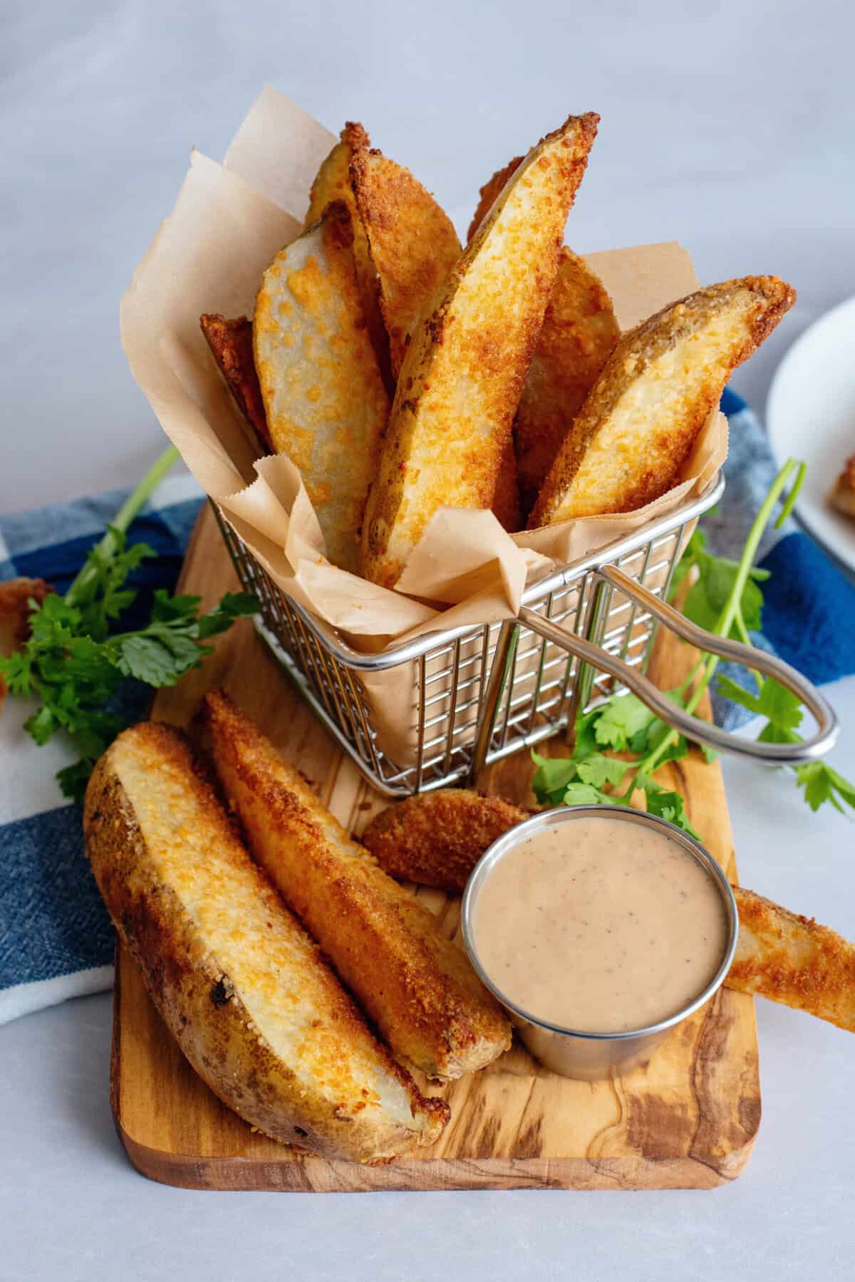 Parmesan oven fries in a basket with sauce on the side.