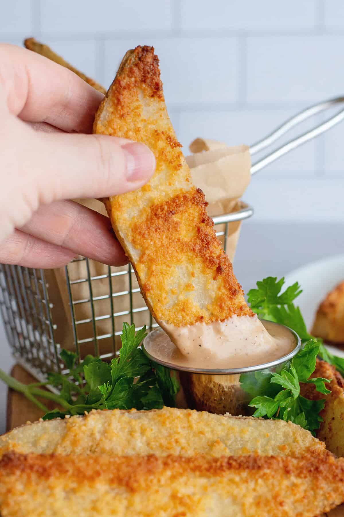 Dipping parmesan oven fries in dipping sauce.