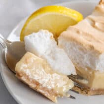 Bite of lemon meringue pie with condensed milk on plate.