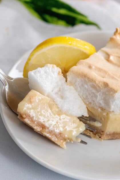 Bite of lemon meringue pie with condensed milk on plate.