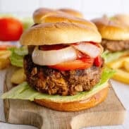 Meatloaf burgers on a wooden serving tray with onion, tomato, and lettuce.