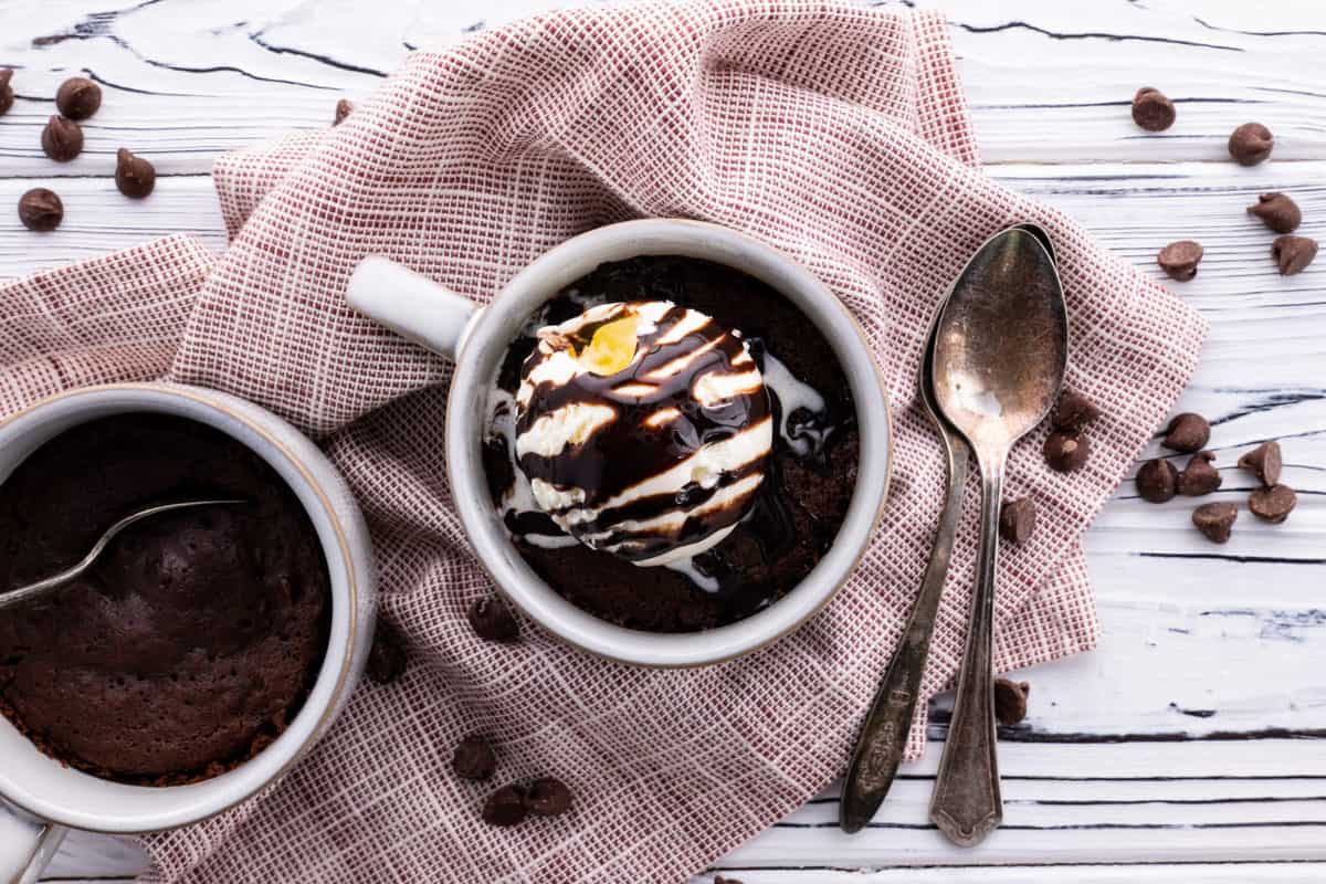 Microwave brownie in a mug with ice cream and chocolate syrup.