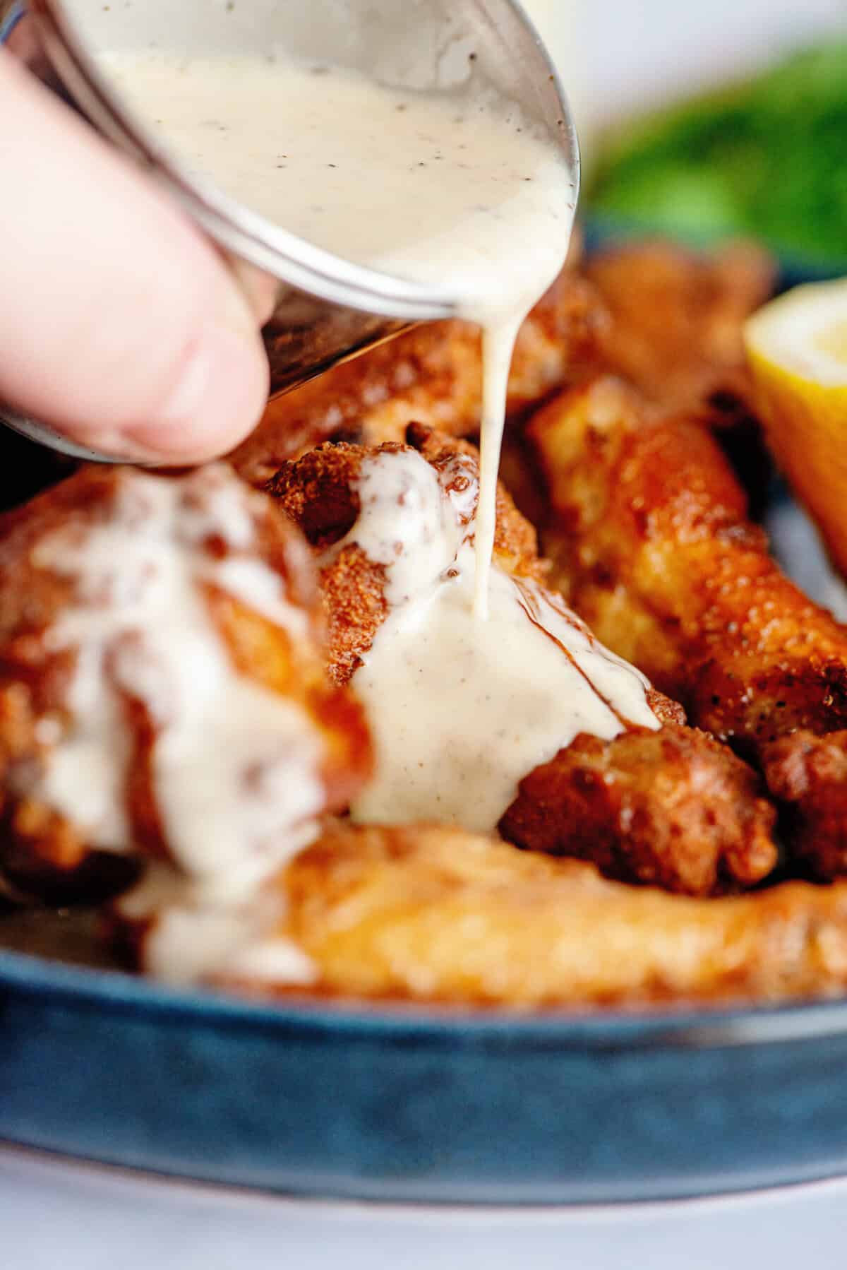 Drenching a chicken wing in Alabama white barbecue sauce.