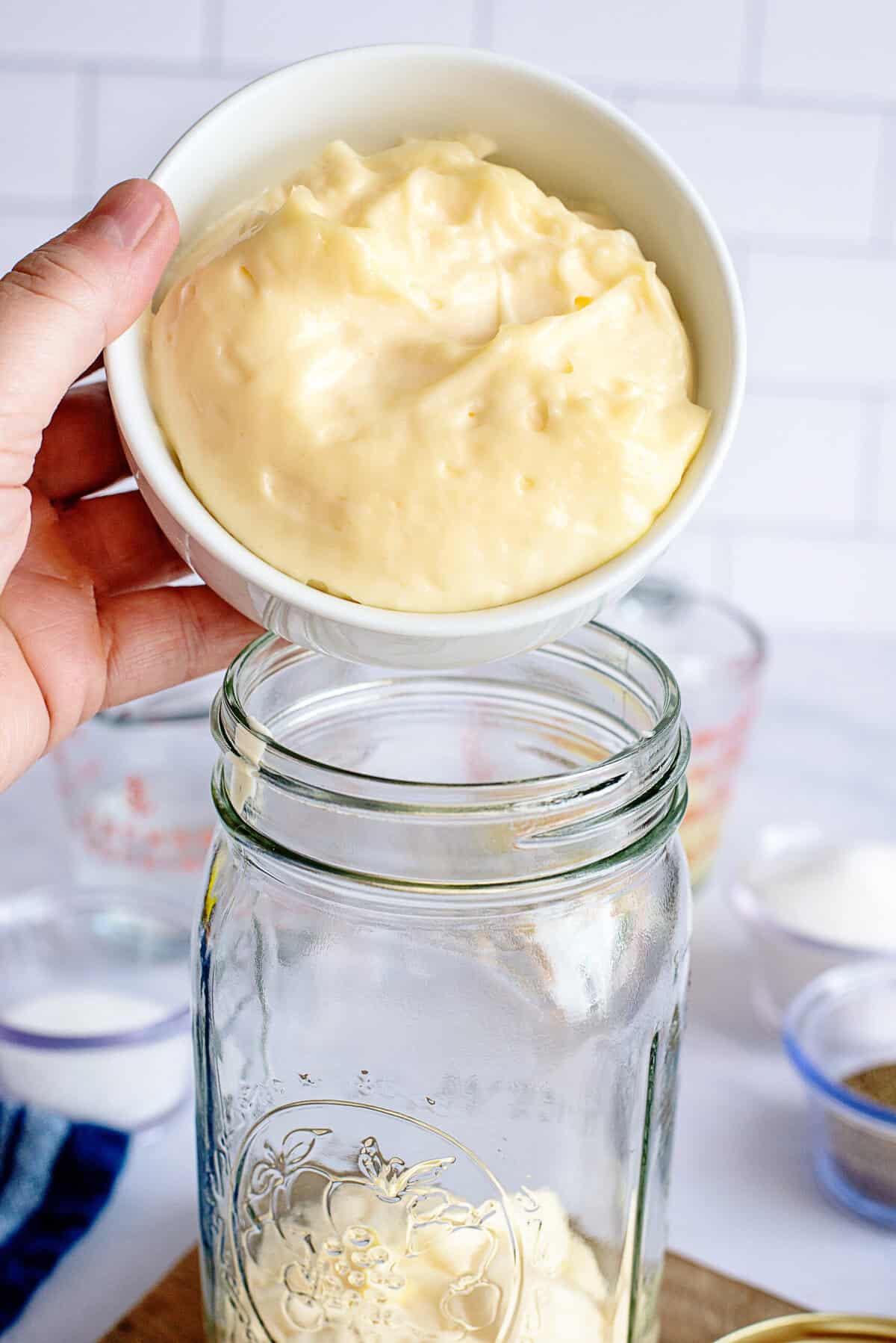 Adding mayonnaise to a mason jar.