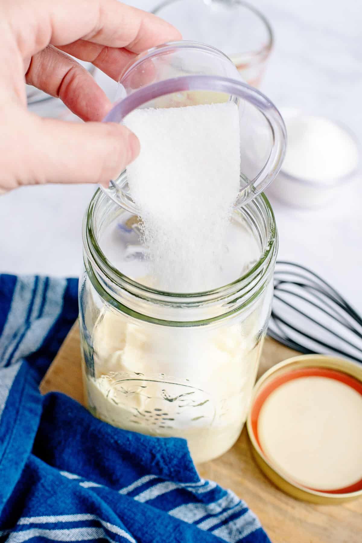 Adding salt to a mason jar of mayonnaise.