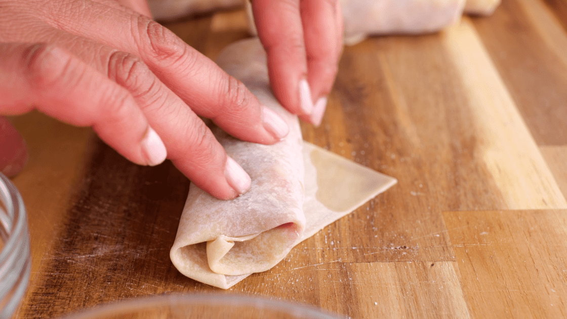 Add water to the open tip of egg roll before sealing.