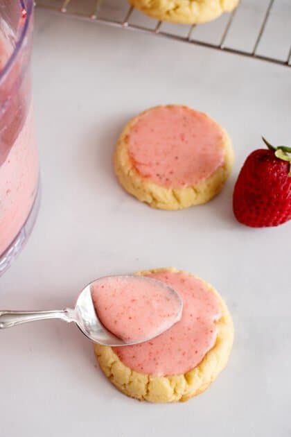 Spoon strawberry frosting over cookies.