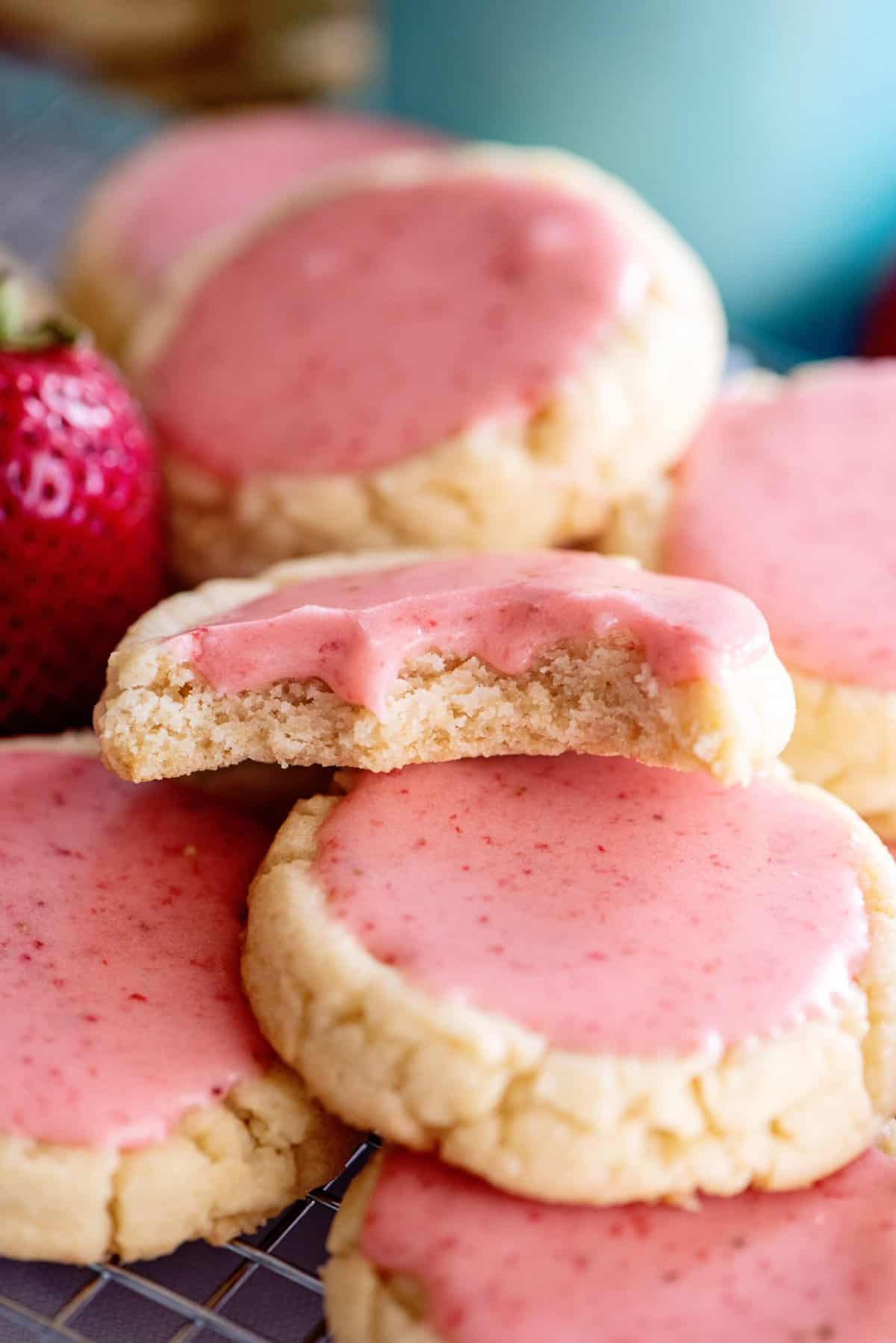 Bite taken out of strawberry frosted cookie.