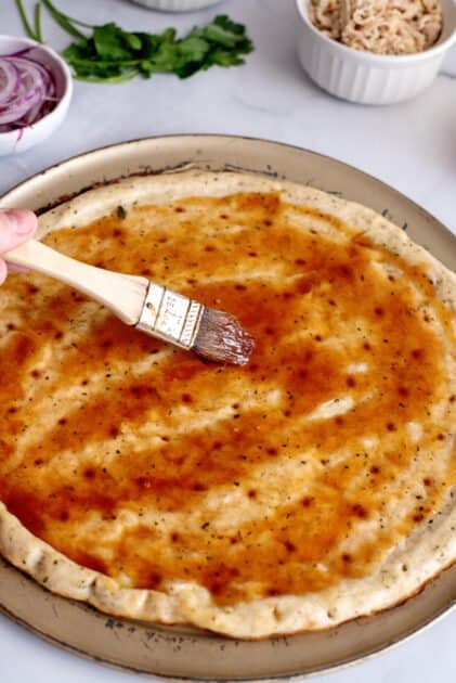 Spread pizza sauce over dough.