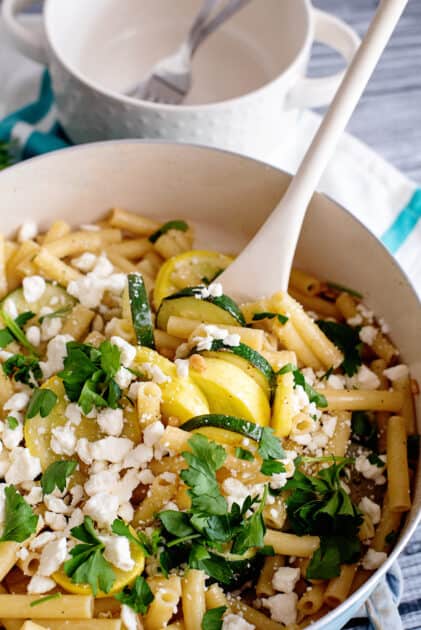 Add crumbled cheese and fresh herbs before serving summer squash pasta.