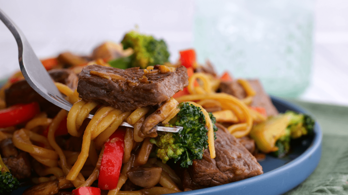Close-up of beef lo mein on fork.