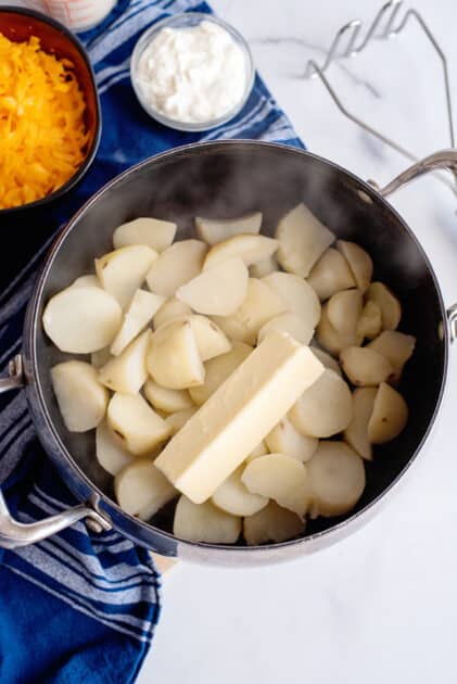 Add stick of butter to drained potatoes in the pot.