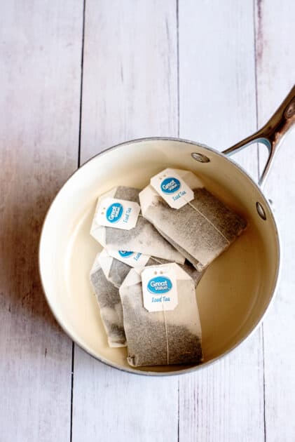 Tea bags in a pot over a gray wooden surface.