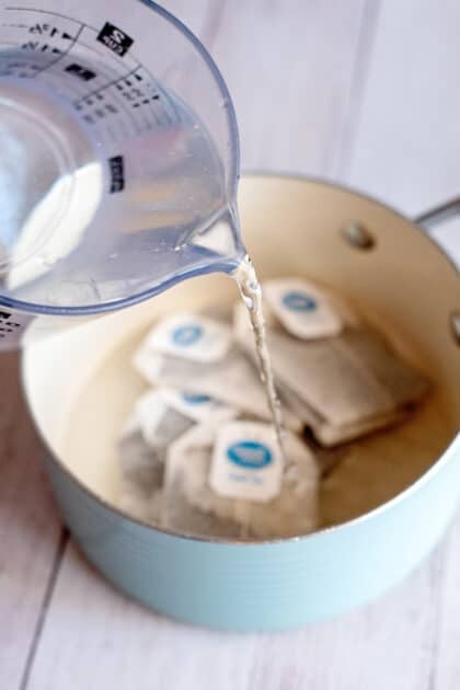 Pouring water in a pot of black tea bags.