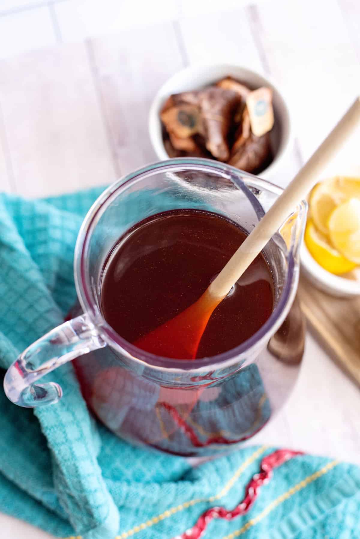 Stirring a pitcher of Southern sweet tea with a wooden spoon.