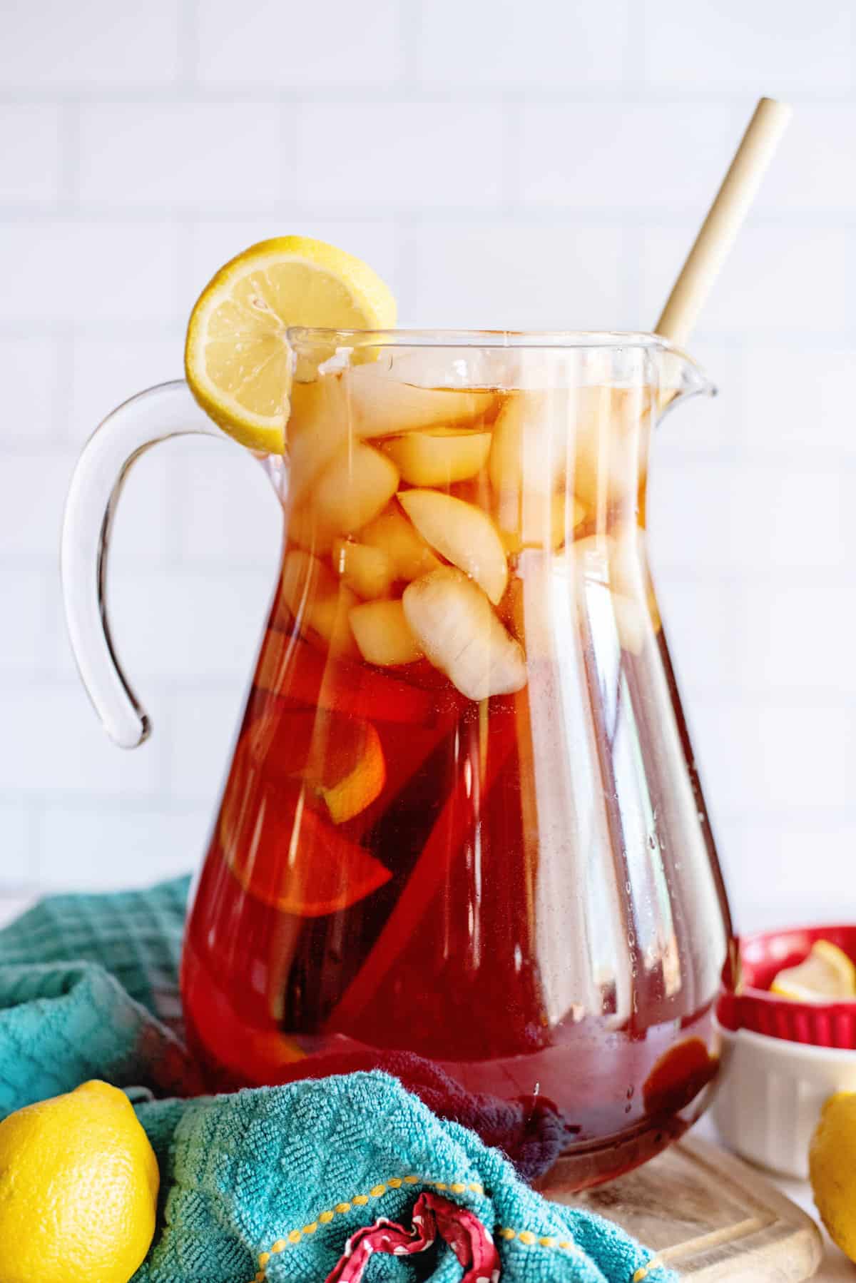 A pitcher of Southern sweet tea with a wooden spoon and lemon wedge.