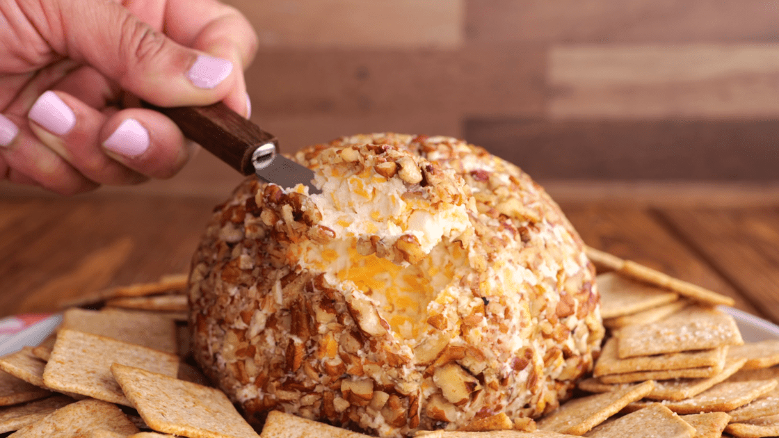 A knife holding a serving of cheese ball.