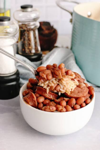 Scooping a spoonful of red beans and rice out of a white bowl.