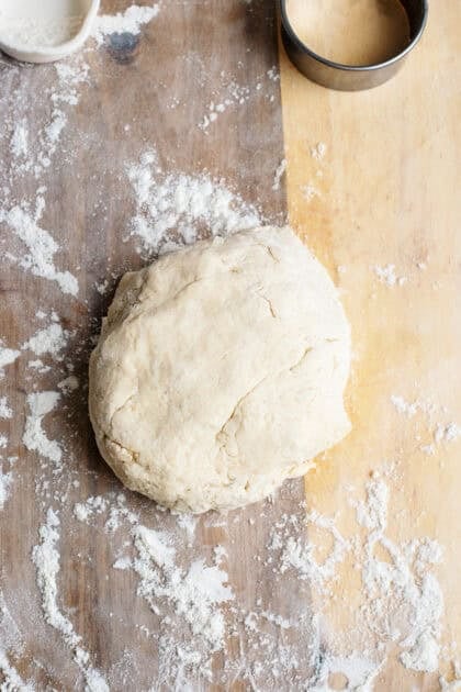A ball of biscuit dough on a floured surface.