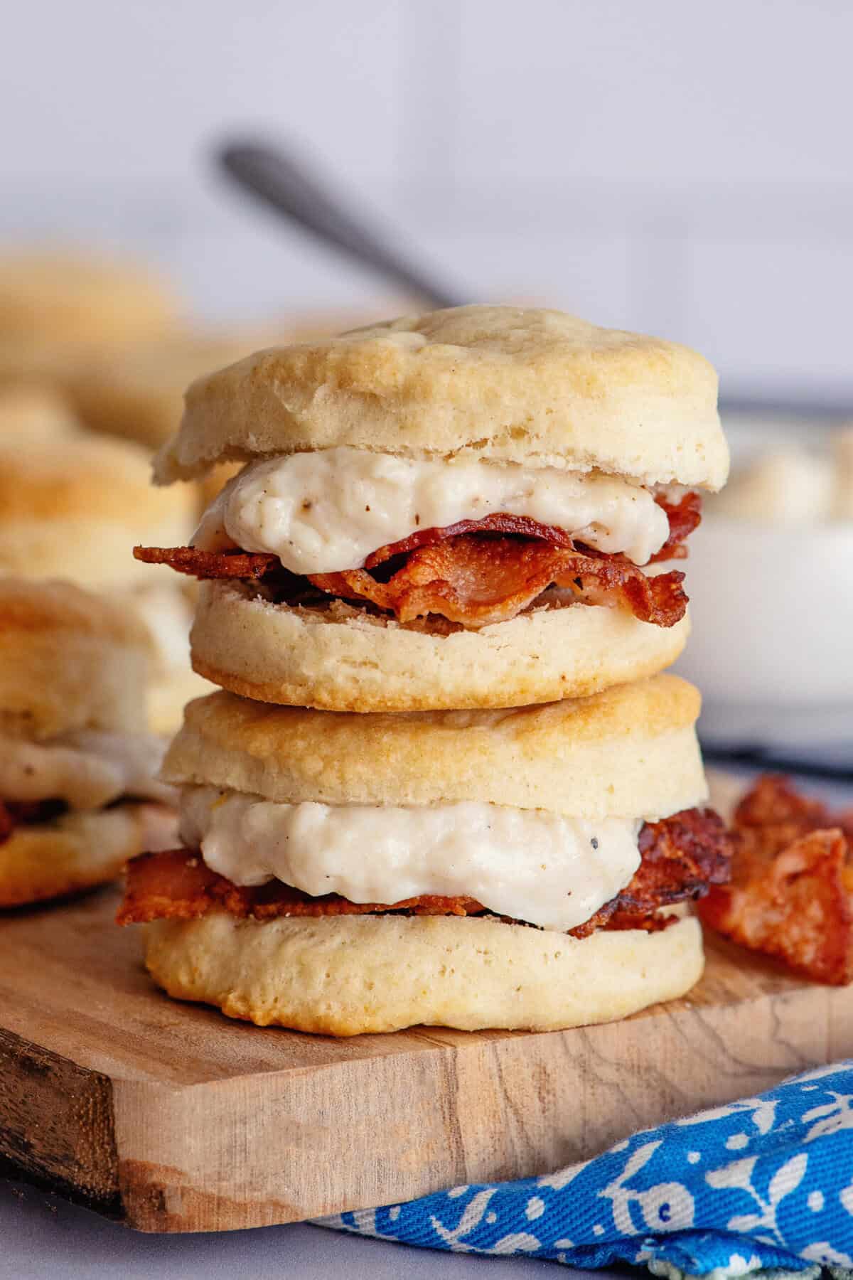 A stack of mouthwatering biscuits with bacon gravy on a wooden serving tray.