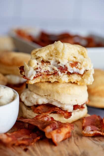 Stacked biscuits and bacon gravy with a bite out of the top biscuit.