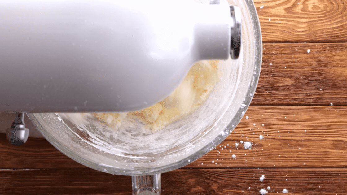 Mixing powdered sugar slowly into bowl.