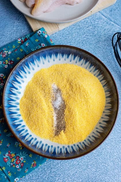 Adding seasoning to a shallow dish of cornmea.l