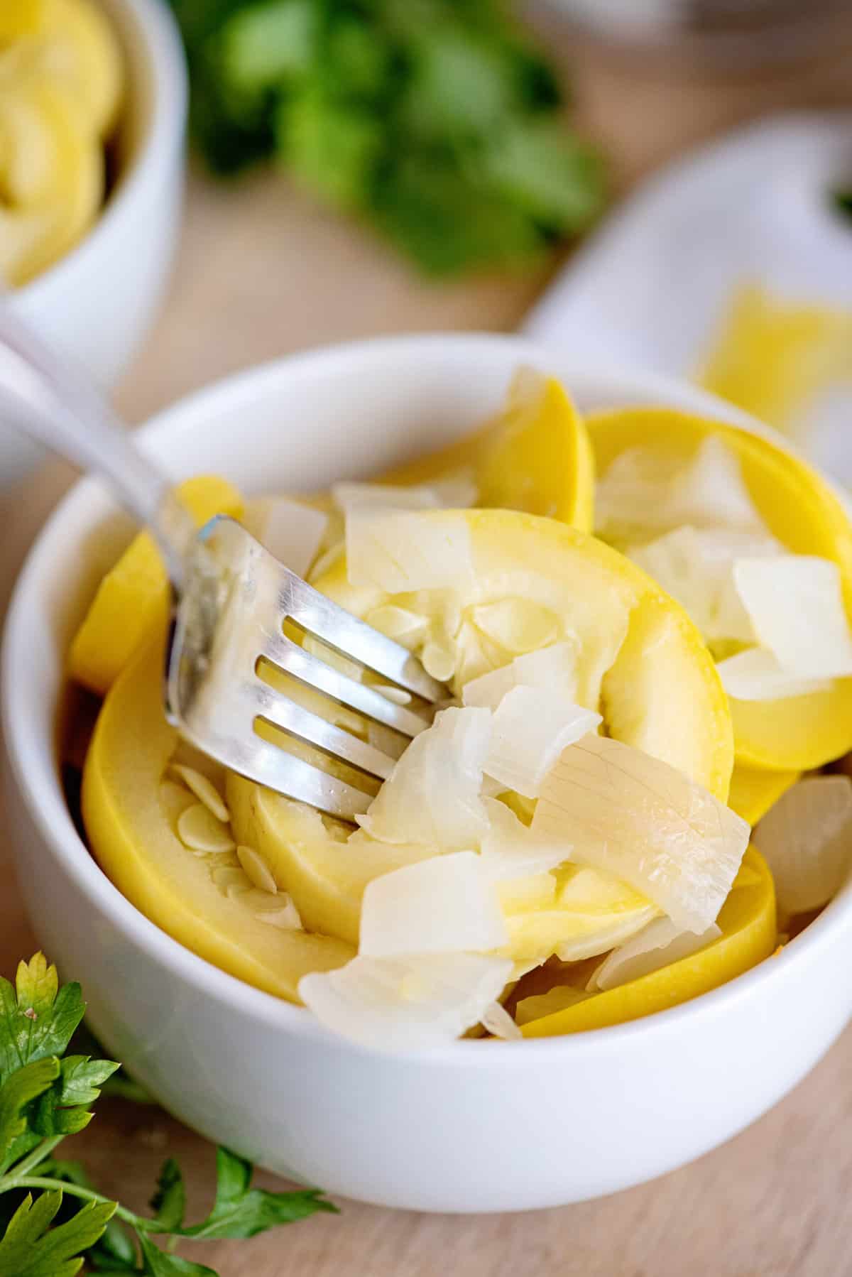 Fork digging into a bowl of boiled squash and onion.