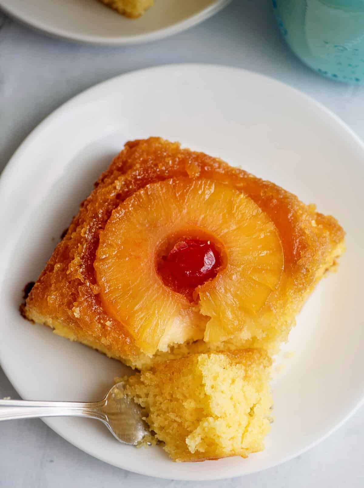A fork digging into a slice of pineapple upside-down cake.