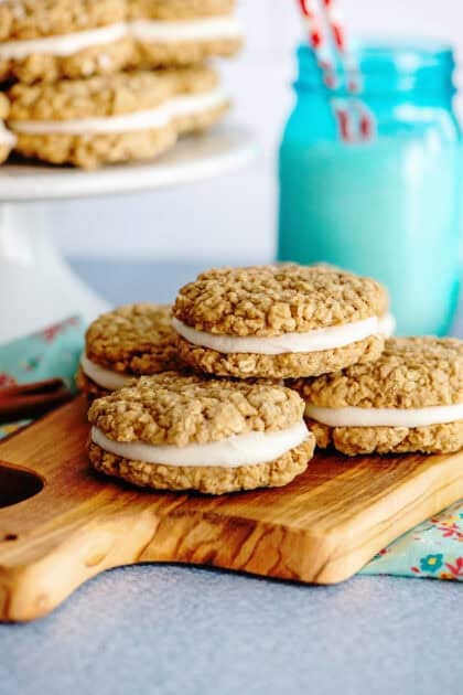 Delicious oatmeal cream pies stacked over a wooden serving board.