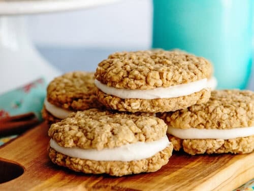 Delicious oatmeal cream pies stacked over a wooden serving board.