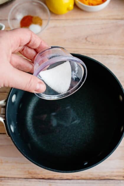 Adding salt to a pot of water.