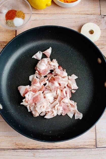 Raw bacon on a skillet getting ready to be cooked.