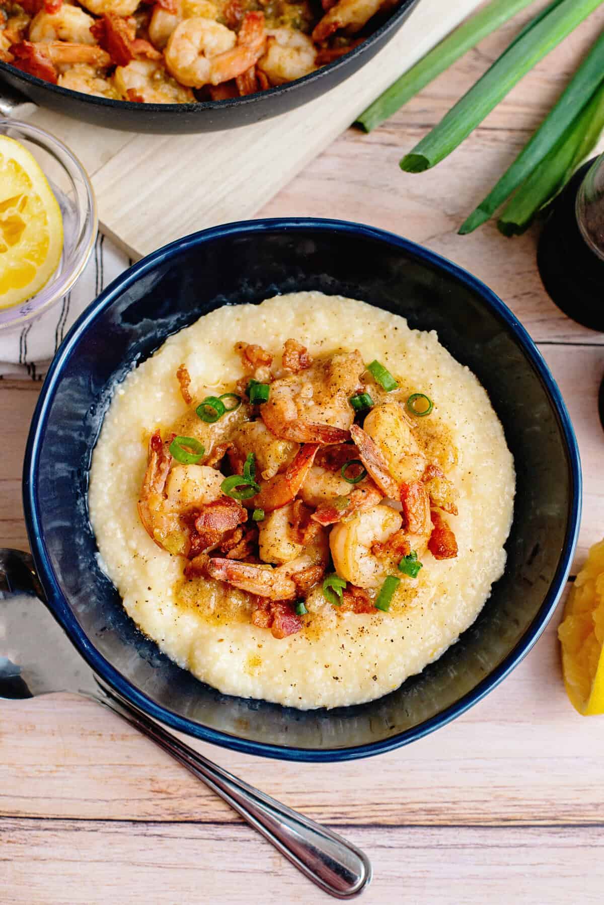 A creamy bowl of Southern shrimp and grits topped with plump, sautéed shrimp, crispy bacon, and a sprinkle of green onions for freshness.