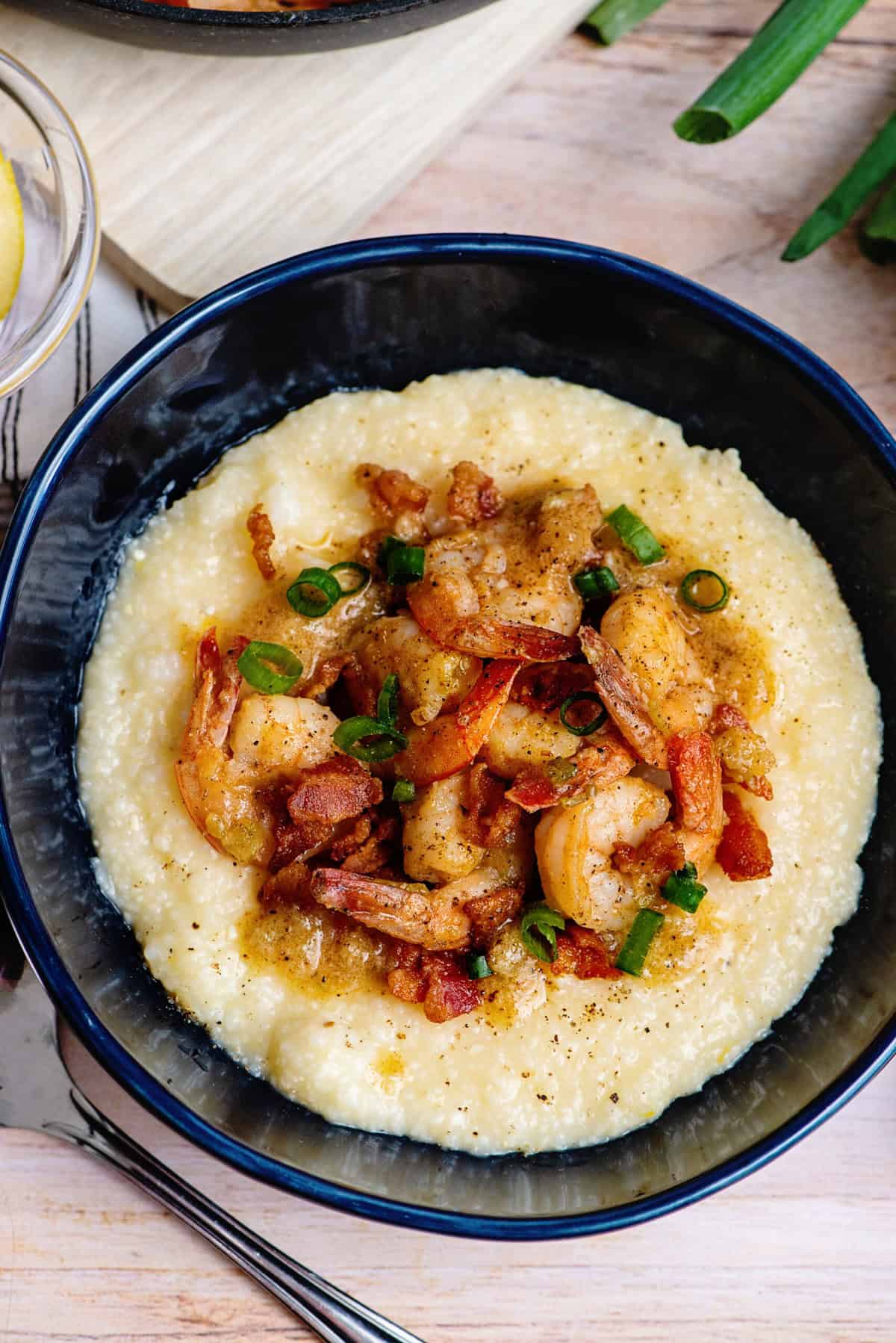 A creamy bowl of Southern shrimp and grits topped with plump, sautéed shrimp, crispy bacon, and a sprinkle of green onions for freshness.