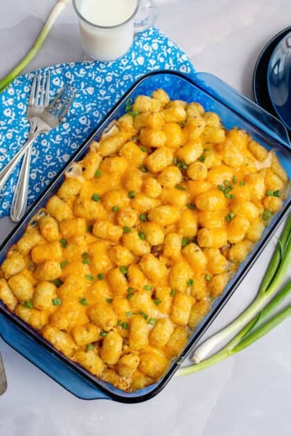 Hot biscuits and gravy tater tot casserole plated with a sprinkle of chopped parsley for freshness.