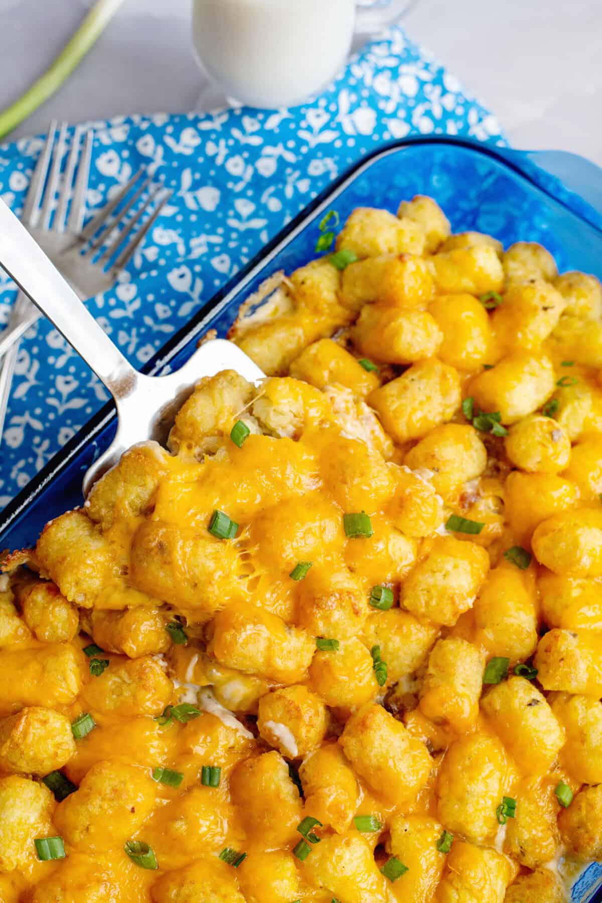 Crispy tater tot topping with deep golden-brown edges, covering a layer of creamy sausage gravy and fluffy biscuit pieces.