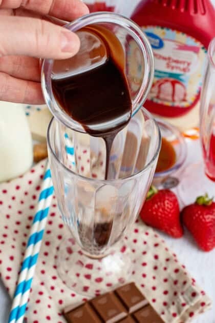 Pouring chocolate syrup in a decorative glass.