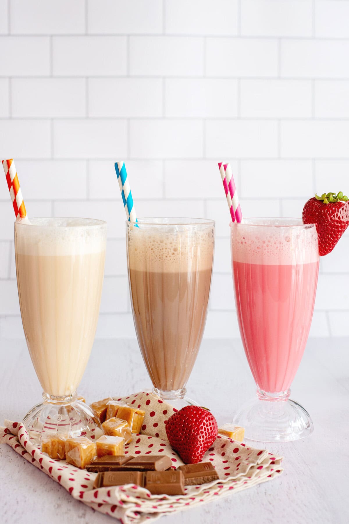 Caramel, chocolate, and strawberry egg creams in decorative glasses.