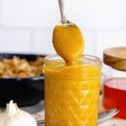 A clean, glass mason jar filled with vibrant Carolina Gold BBQ sauce.