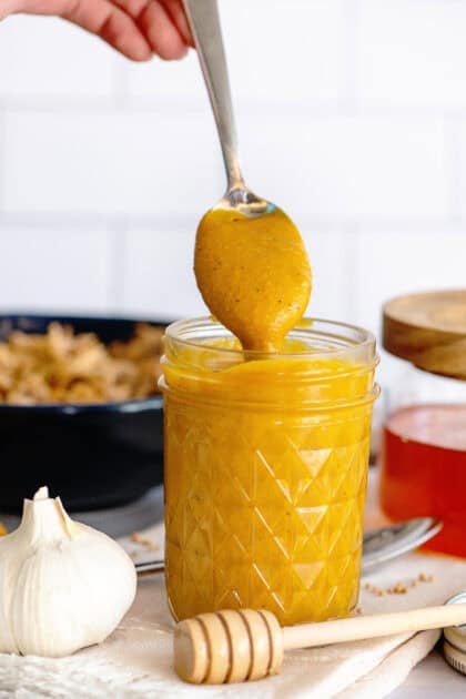 A clean, glass mason jar filled with vibrant Carolina Gold BBQ sauce.